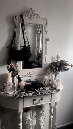 a white table topped with a mirror next to a vase filled with flowers and candles