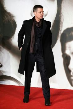 a man standing on top of a red carpet in front of a wall with a movie poster behind him