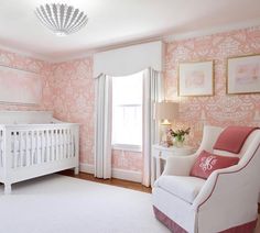 a baby's room with pink and white wallpaper, a crib, and a chandelier