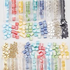 there are many different colors of beads in the plastic tube and on the white background