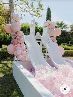 an inflatable water slide with pink and white balloons