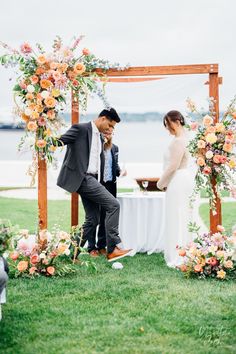 a bride and groom are getting married in front of an arch with flowers on it