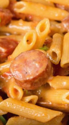 a close up view of some pasta with sausage and other things in it on the table