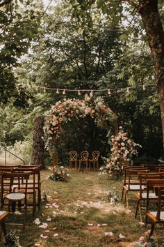 an outdoor ceremony setup with wooden chairs and flowers on the aisle, surrounded by trees