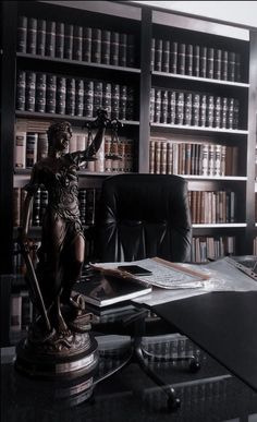 a desk with a statue on top of it next to a book shelf filled with books