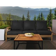 a wooden table sitting on top of a patio next to a couch and coffee table