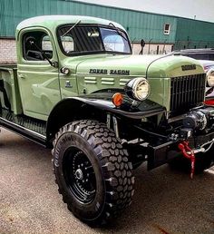 an old green truck parked in a parking lot