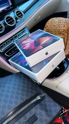 an apple box sitting on top of a car dashboard next to other bags and purses