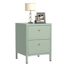 a green nightstand with two drawers and a lamp on top of the night stand next to it