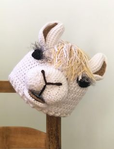 a crocheted llama's head on top of a wooden chair