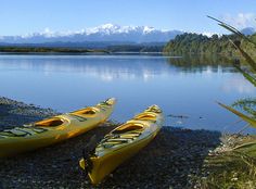 two yellow kayaks sitting on the shore of a lake