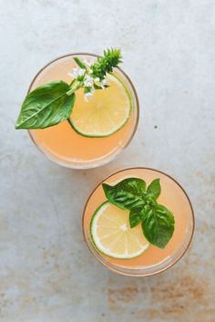 two glasses filled with lemonade and garnished with mint leaves on a marble surface