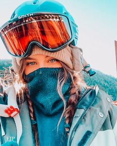 a woman wearing ski goggles and a scarf on top of her head is taking a selfie