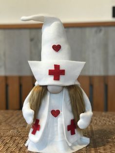 a stuffed animal wearing a white hat with red crosses on it's head and long hair