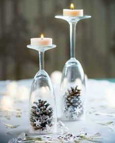 two wine goblets with pine cones in them on a table covered in snow