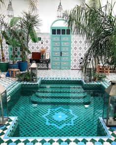 an indoor pool with tiled walls and flooring, surrounded by potted palm trees