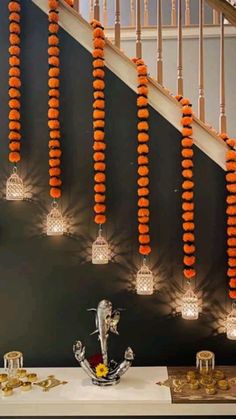 some lights that are hanging from the side of a stair case with orange decorations on it