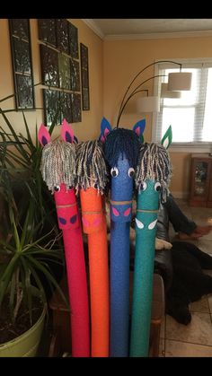 four colorful horse head umbrellas in front of a potted plant on the floor