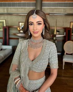 a woman in a gold and white lehenga with jewelry on her head, standing in a hallway