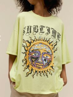 a woman wearing a yellow t - shirt with an image of the sun on it