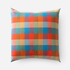 an orange and blue plaid pillow on a white background