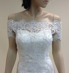 a mannequin wearing a white wedding dress with off the shoulder lace trims