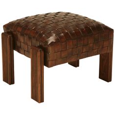 the foot stool is made out of wood and has a woven leather seat cushion on it