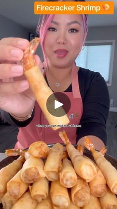 a woman is holding up a large plate of food with shrimp sticks in it and the video appears to be showing her