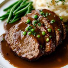 meatloaf with gravy, mashed potatoes and green beans on a plate