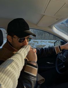 a man sitting in the driver's seat of a car with his hand on the steering wheel