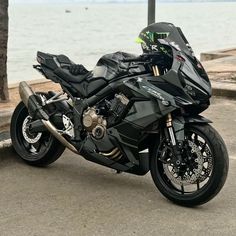 a black motorcycle parked next to the ocean