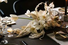 the table is set with white flowers and silverware