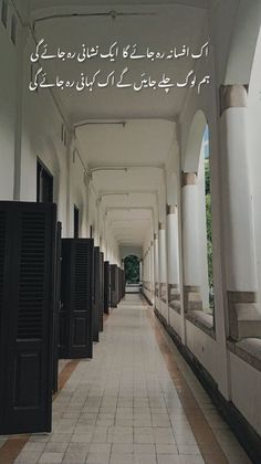 the hallway is lined with black doors and white walls, which have arabic writing on them