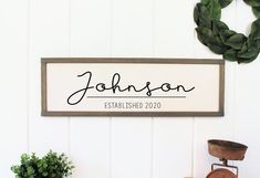 a personalized sign hanging on the wall next to a potted plant and chair