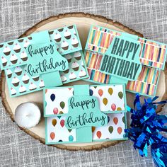 happy birthday cards with cupcakes and candles on a wood slice next to blue streamers