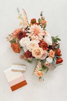 a bouquet of flowers and a card on a white surface with a color swatch