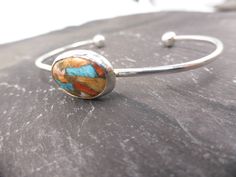 This delightful cuff bangle has been hand made using 100% recycled sterling silver.  It has been hallmarked at the London Assay Office as shown in one of my pictures and will be presented in my signature gift box. The cuff measures approximately 63mm in diameter and holds a colourful Mohave Copper cabochon at it's centre. All of my packaging is eco-friendly. My gift box is made from 40% recycled content and is 100% recyclable (excluding the foam insert).  My environmentally friendly padded envel Unique Oval Cuff Bracelet For Gift, Oval Sterling Silver Cuff Bracelet Gift, Artisan Sterling Silver Bangle As Gift, My Gift, My Signature, Recycled Silver, Everyday Earrings, Silver Cuff Bracelet, Recycled Sterling Silver