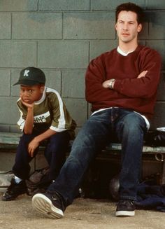 two young men sitting on a bench next to each other