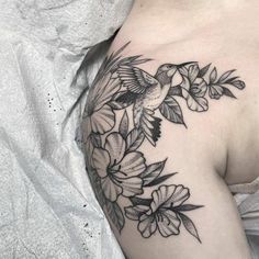 a woman's shoulder with flowers and a hummingbird tattoo on her left arm