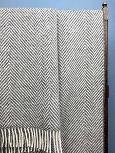 a white and gray blanket sitting on top of a wooden headboard next to a blue wall