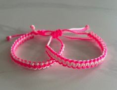 two pink and white bracelets sitting on top of each other