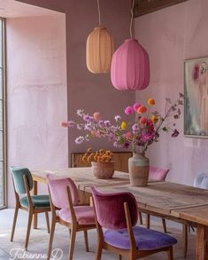 a wooden table topped with purple chairs next to a vase filled with flowers