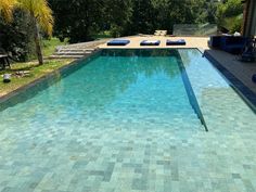 an empty swimming pool with lounge chairs and trees in the backgroung area