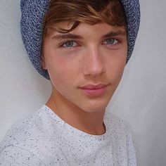 a young man wearing a blue hat and looking at the camera with a serious look on his face