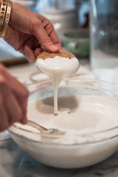 a person is dipping some food into a bowl with white icing on the side