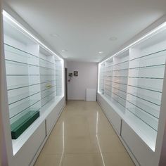 an empty hallway with several glass shelves on both sides and one light at the end