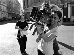 two women standing in front of a camera on the street