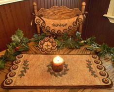 a table with a candle on top of it next to a chair and rug covered in holly leaves