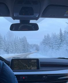 the dashboard of a car on a snowy road with snow covered trees in the background