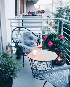 a balcony with two chairs and a small table on it, next to potted plants